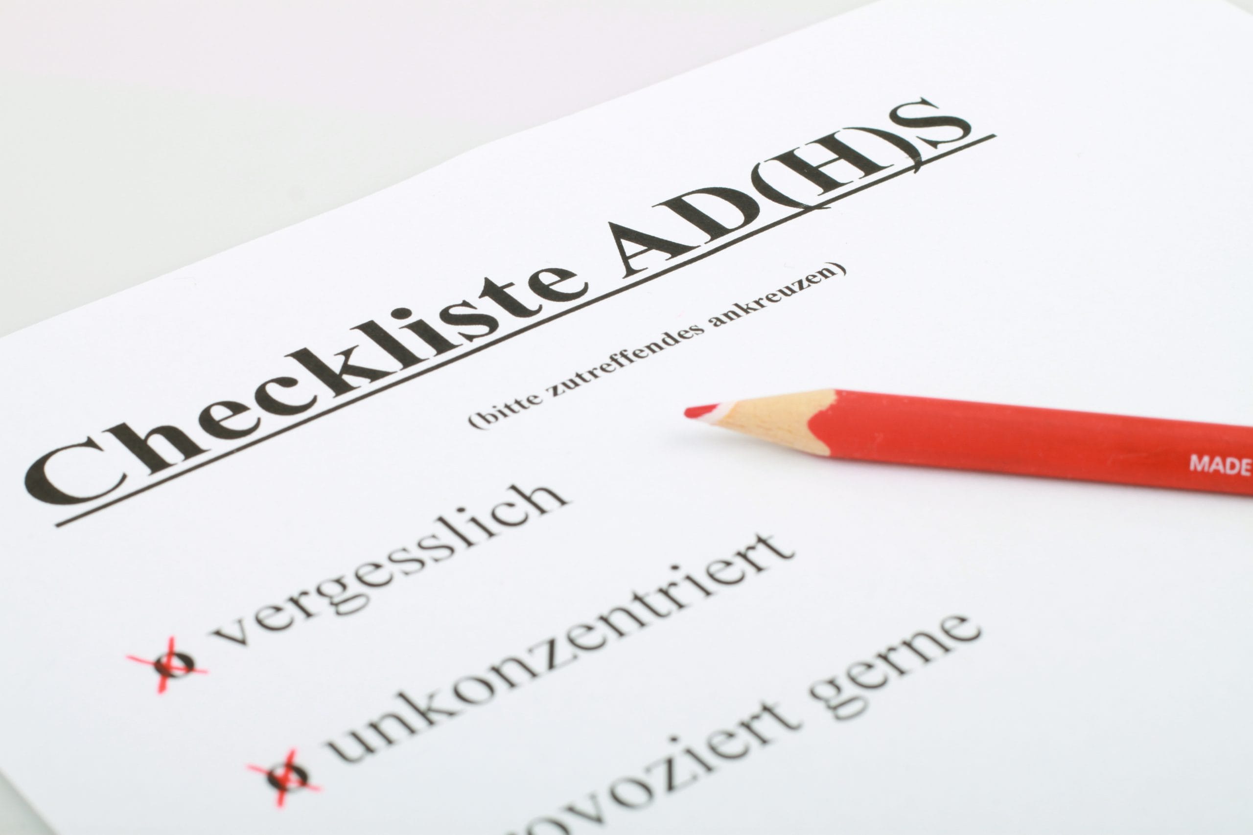 Eine Checkliste ADHS mit einem roten Bleistift, die „vergesslich“, „unkonzentriert“ und „provoziert gerne“ anzeigt und markiert ist. Sie vermittelt die typischen Anzeichen, die ein Fragebogen ADHS oder ein ADHS Selbsttest für Erwachsene ermitteln kann.