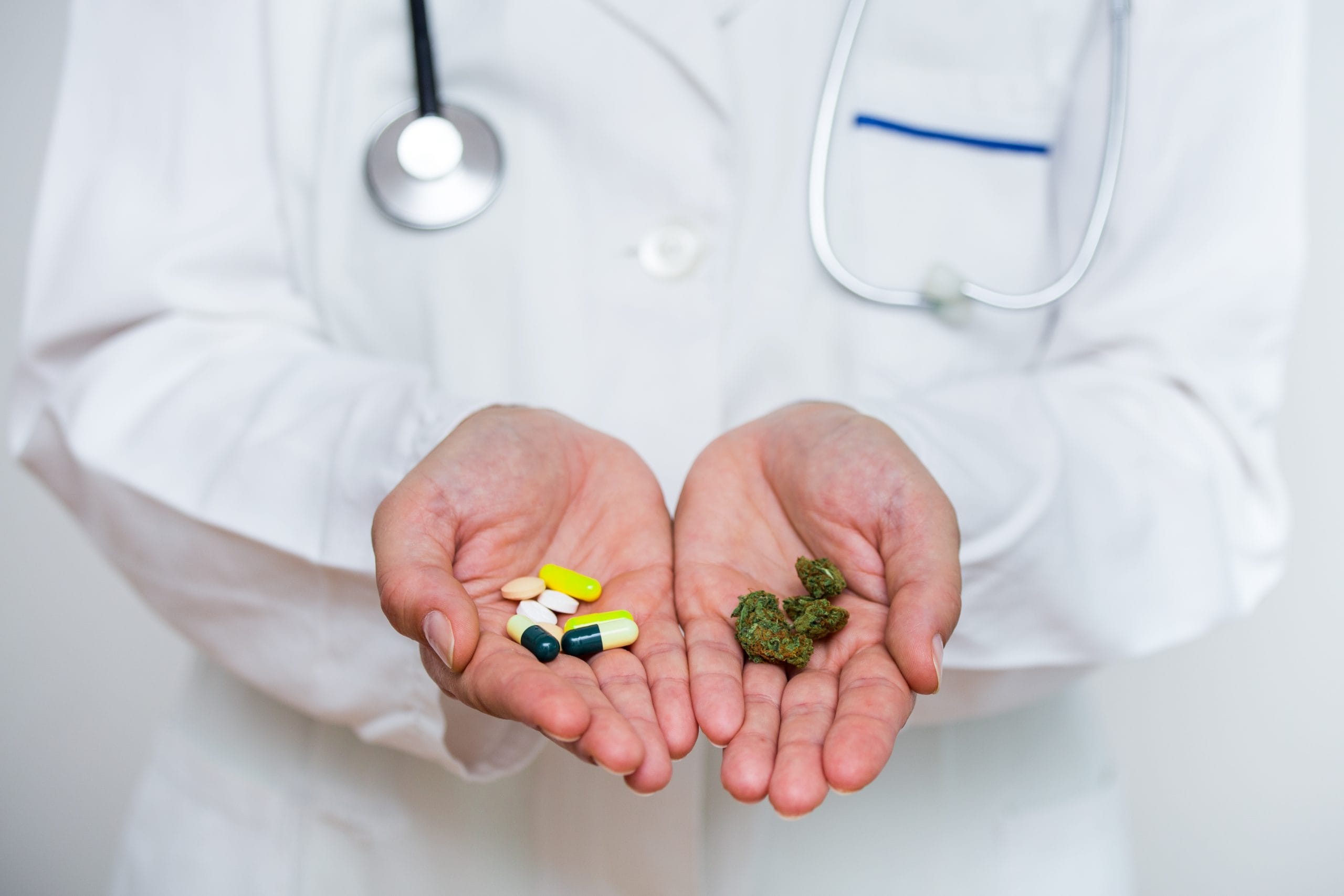 Arzt zeigt zwei Hände mit verschiedenen Medikamenten, einschließlich Cannabis und Pillen, als Behandlungsoptionen.