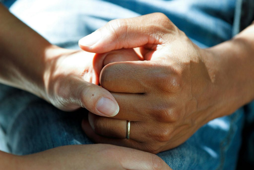 Zwei Hände halten sich unterstützend – eine Patientin im Gespräch mit einer vertrauten Person. Symbolbild für einfühlsame Therapie in der Schweiz.